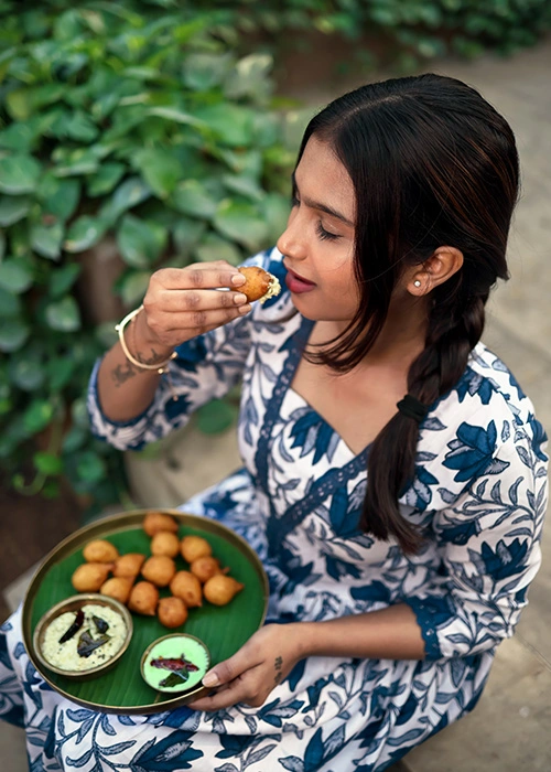 Woman enjoying South Indian snacks like vada served with chutney