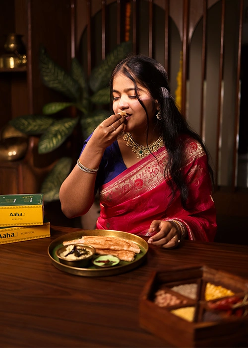 Woman enjoying a bite of South Indian food in a restaurant