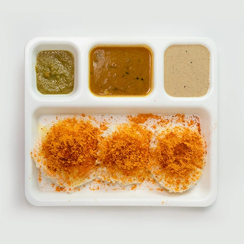 South Indian ghee podi idly served with chutney and sambar, topped with ghee and spice powder