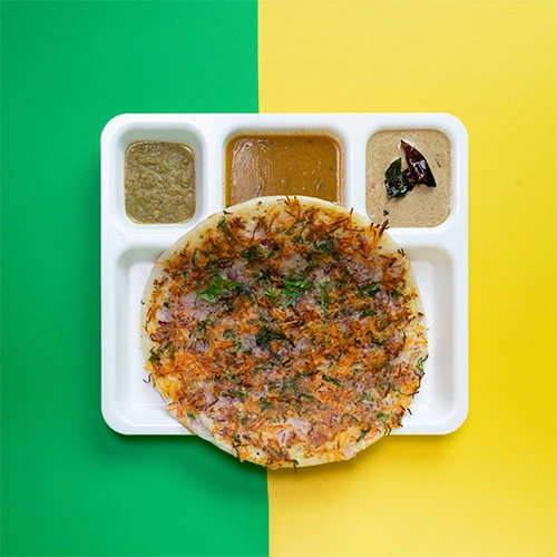 South Indian uthappam topped with fresh onions and served with chutney