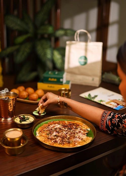 A person enjoying South Indian food, including dosa and sambar