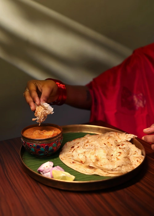 Woman eating chapati with curry in a South Indian restaurant